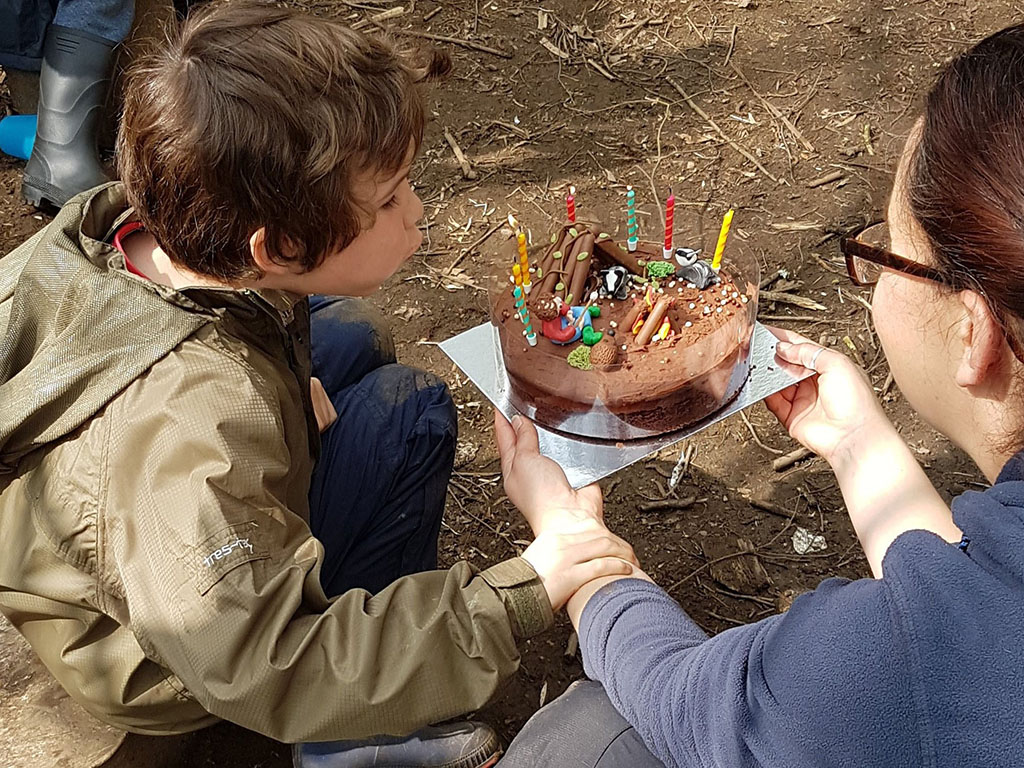 boy getting a birthday cake in the forest